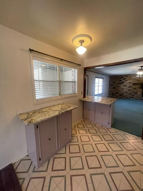 kitchen with light stone counters, light floors, and gray cabinetry