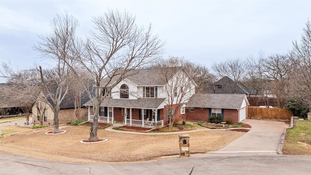 traditional-style home featuring brick siding, a porch, concrete driveway, fence, and a garage