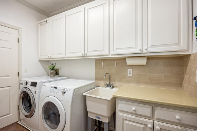 laundry room with a sink, washing machine and dryer, cabinet space, and crown molding