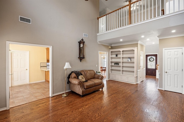 living area featuring baseboards, crown molding, visible vents, and wood finished floors