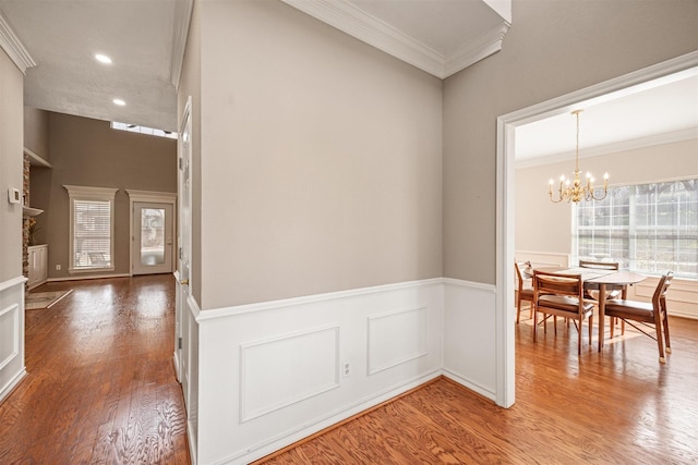 dining area with wainscoting, ornamental molding, wood finished floors, an inviting chandelier, and recessed lighting