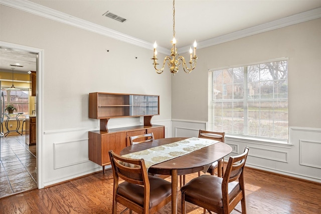 dining room with a wainscoted wall, wood finished floors, visible vents, and a healthy amount of sunlight