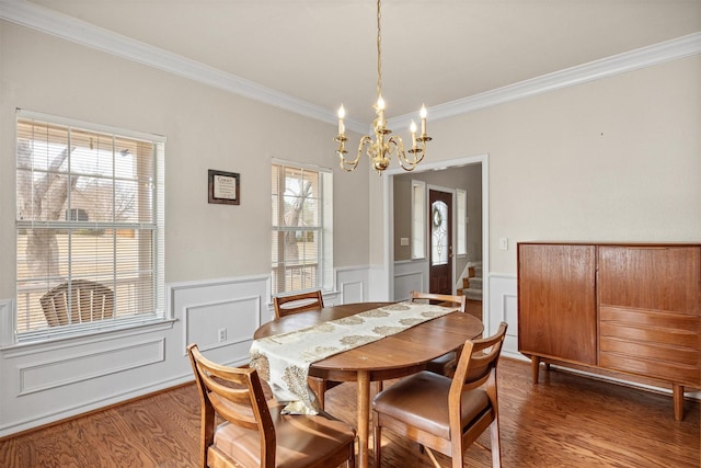 dining space featuring wainscoting, a chandelier, wood finished floors, and ornamental molding