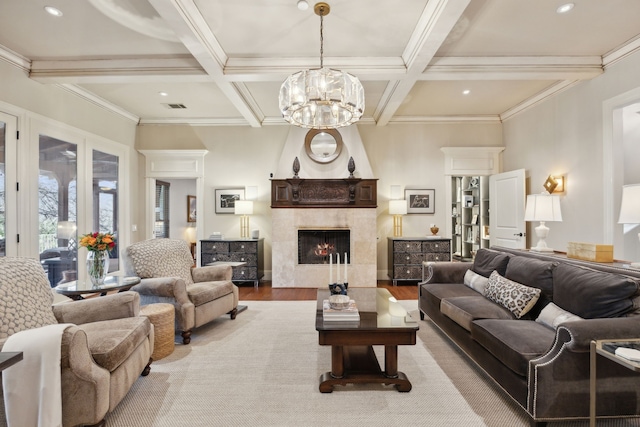 living room with wood finished floors, visible vents, beam ceiling, a tiled fireplace, and an inviting chandelier