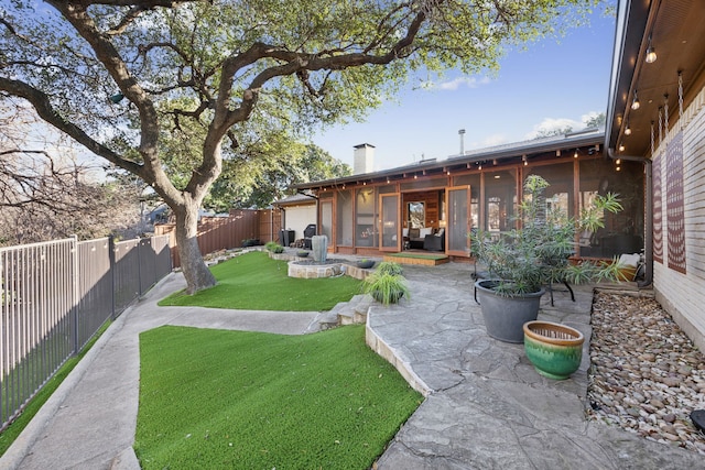 view of yard with a sunroom, a fenced backyard, and a patio