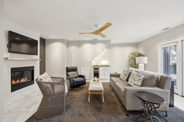 living area with marble finish floor, recessed lighting, wine cooler, and a glass covered fireplace