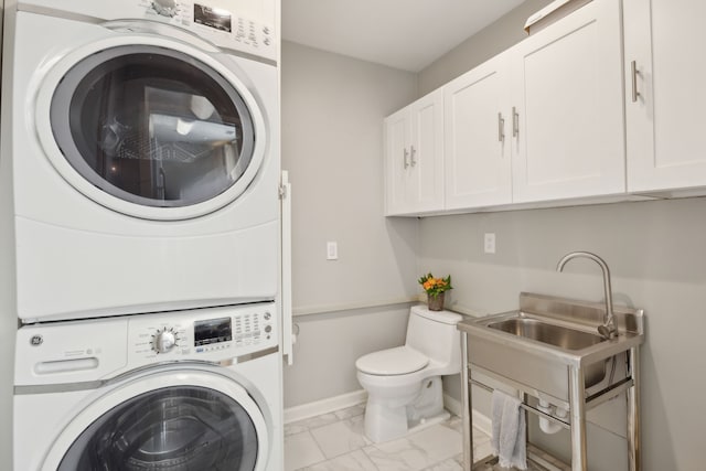 washroom with laundry area, a sink, baseboards, stacked washer / drying machine, and marble finish floor