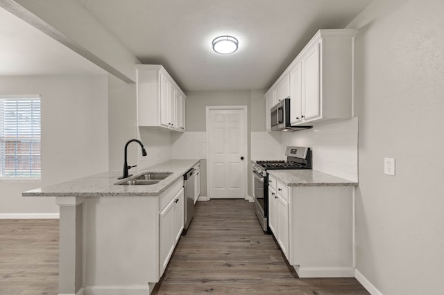 kitchen featuring appliances with stainless steel finishes, white cabinets, a sink, and decorative backsplash