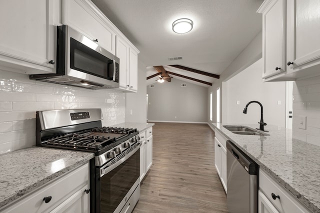 kitchen with visible vents, ceiling fan, vaulted ceiling with beams, stainless steel appliances, and a sink