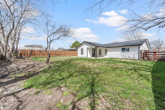 rear view of house with a fenced backyard and a yard