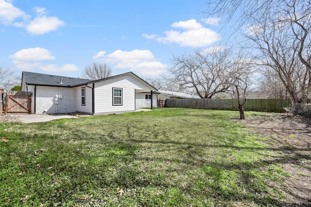 view of yard with a fenced backyard and a gate