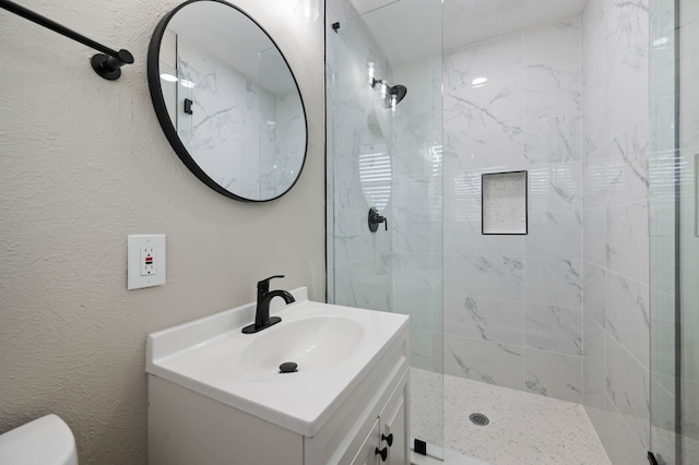 bathroom with a textured wall, a stall shower, and vanity