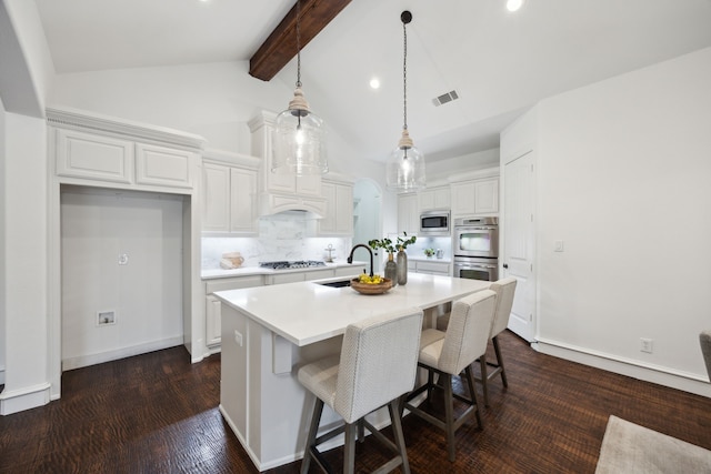 kitchen featuring visible vents, an island with sink, stainless steel appliances, light countertops, and a sink