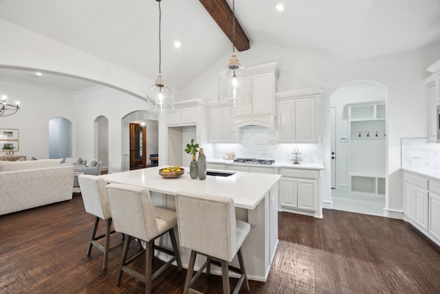 kitchen with beam ceiling, light countertops, backsplash, and a breakfast bar area