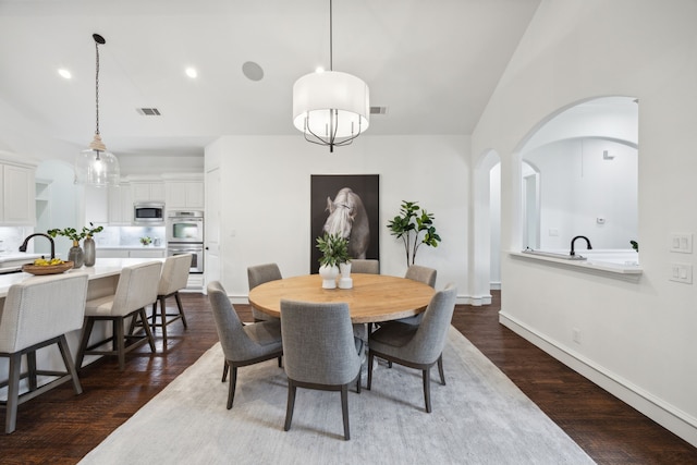 dining space with arched walkways, dark wood-style flooring, visible vents, and baseboards