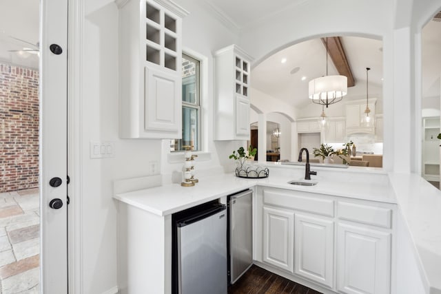 kitchen featuring lofted ceiling with beams, glass insert cabinets, white cabinetry, a sink, and stainless steel refrigerator