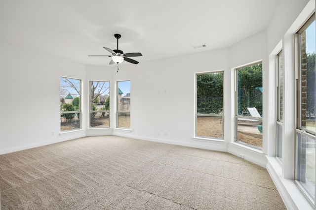 carpeted empty room with visible vents, ceiling fan, and baseboards