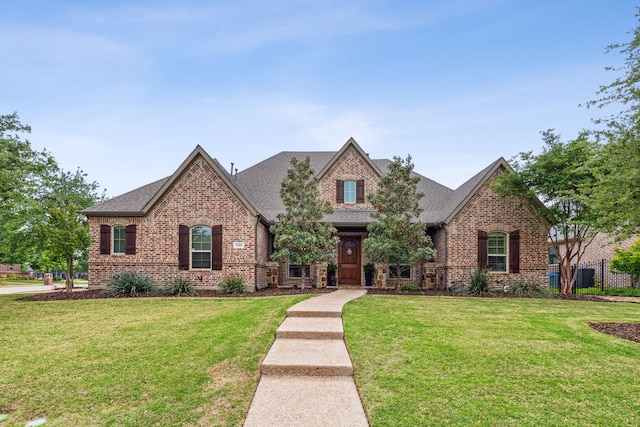 view of front of house featuring brick siding, a front yard, fence, and a shingled roof