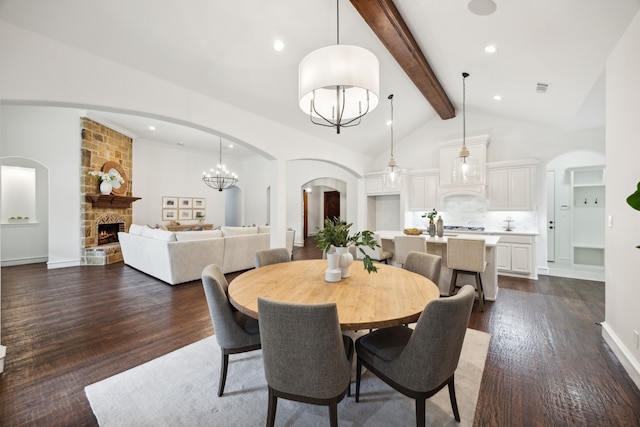 dining area with dark wood-style flooring, visible vents, a stone fireplace, high vaulted ceiling, and beamed ceiling