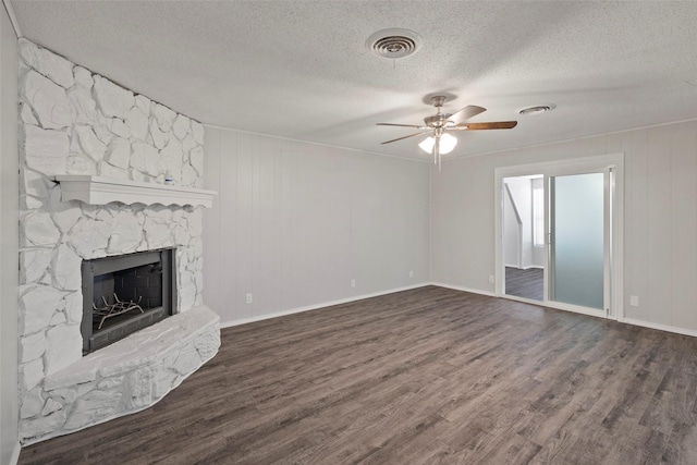 unfurnished living room featuring visible vents, ceiling fan, a stone fireplace, and wood finished floors