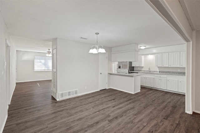 kitchen featuring visible vents, white cabinets, dark wood-style floors, pendant lighting, and ceiling fan with notable chandelier