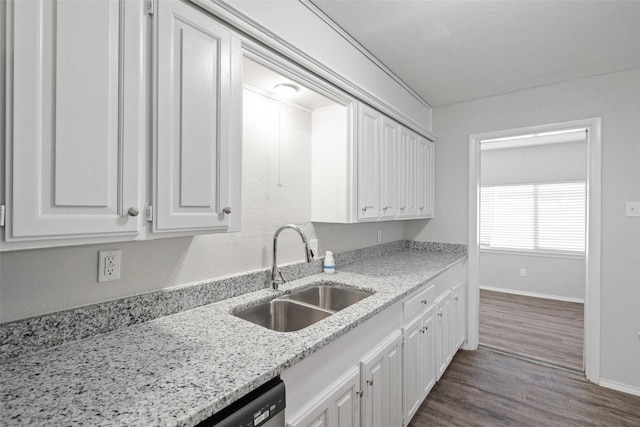 kitchen featuring dark wood-type flooring, white cabinetry, a sink, light stone countertops, and baseboards