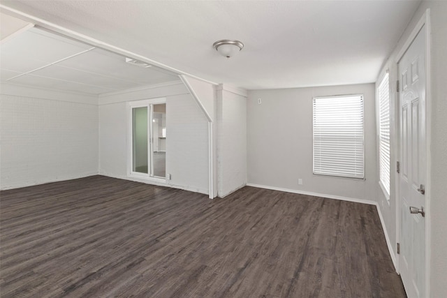 unfurnished room with brick wall and dark wood-style flooring