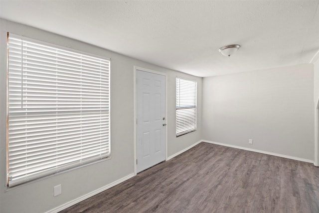 foyer with a textured ceiling, wood finished floors, and baseboards