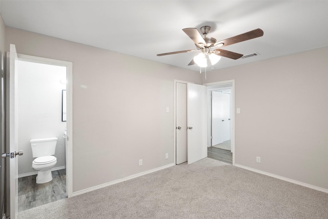 unfurnished bedroom featuring baseboards, visible vents, a ceiling fan, ensuite bathroom, and carpet flooring