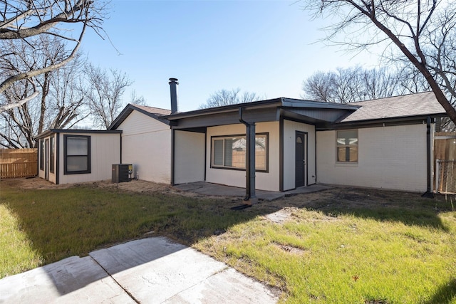 back of house featuring a yard, brick siding, fence, and central air condition unit