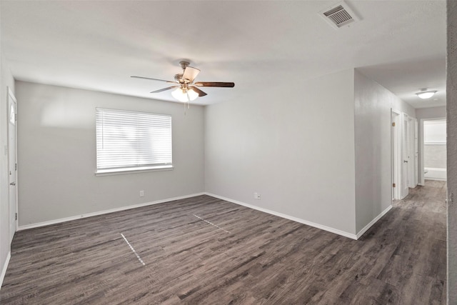 unfurnished room with dark wood-style floors, ceiling fan, visible vents, and baseboards