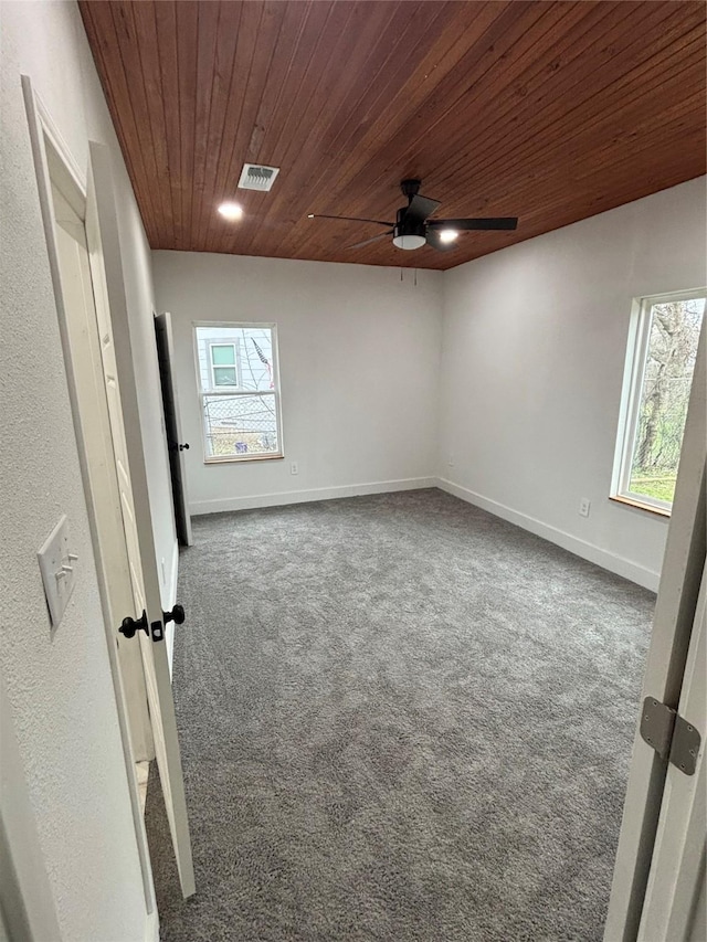 carpeted empty room with wooden ceiling, plenty of natural light, visible vents, and baseboards