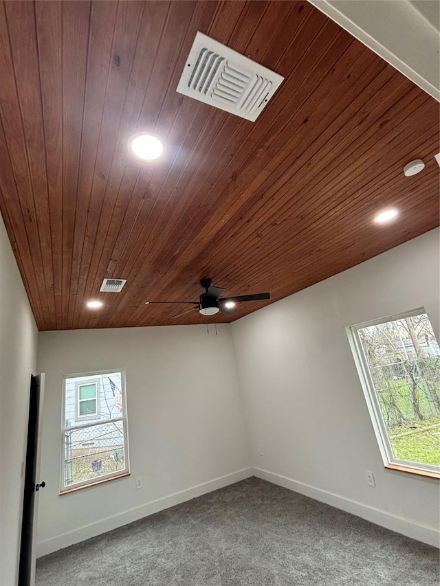 carpeted empty room featuring plenty of natural light, visible vents, and baseboards