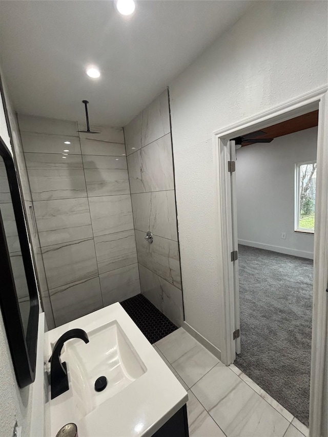 bathroom with tiled shower, recessed lighting, vanity, and baseboards