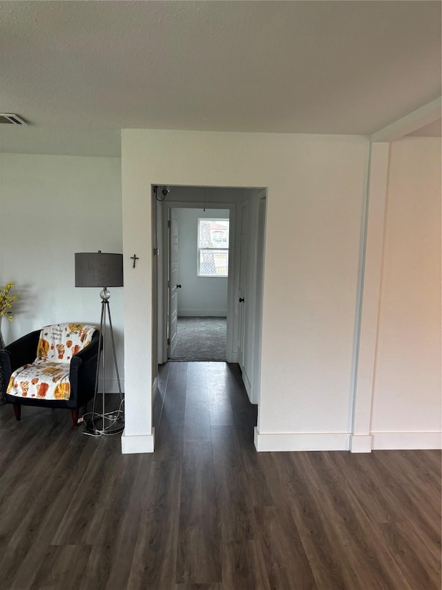 corridor with baseboards, visible vents, and dark wood finished floors