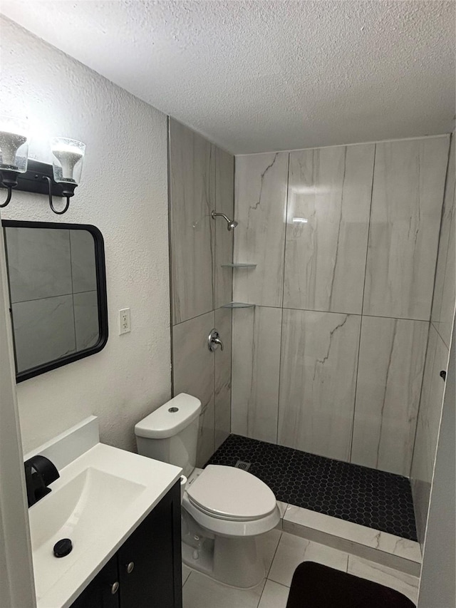 full bath featuring a textured ceiling, a textured wall, toilet, vanity, and a tile shower