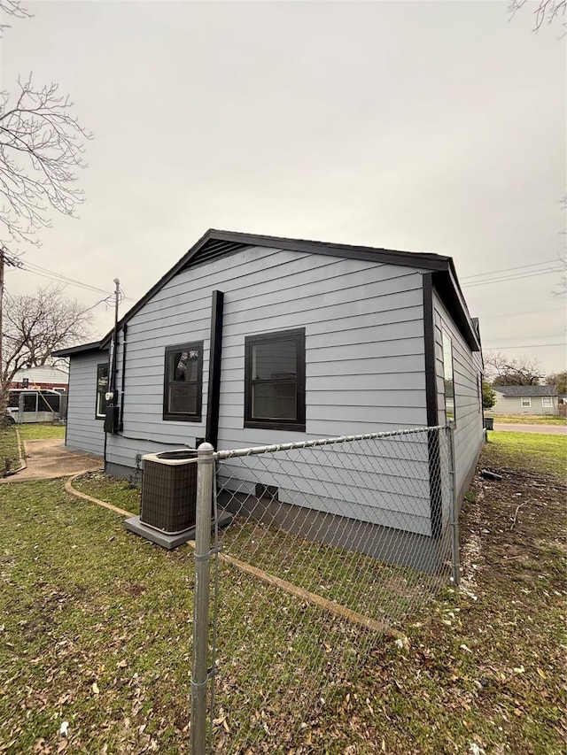 view of side of property with a lawn and cooling unit