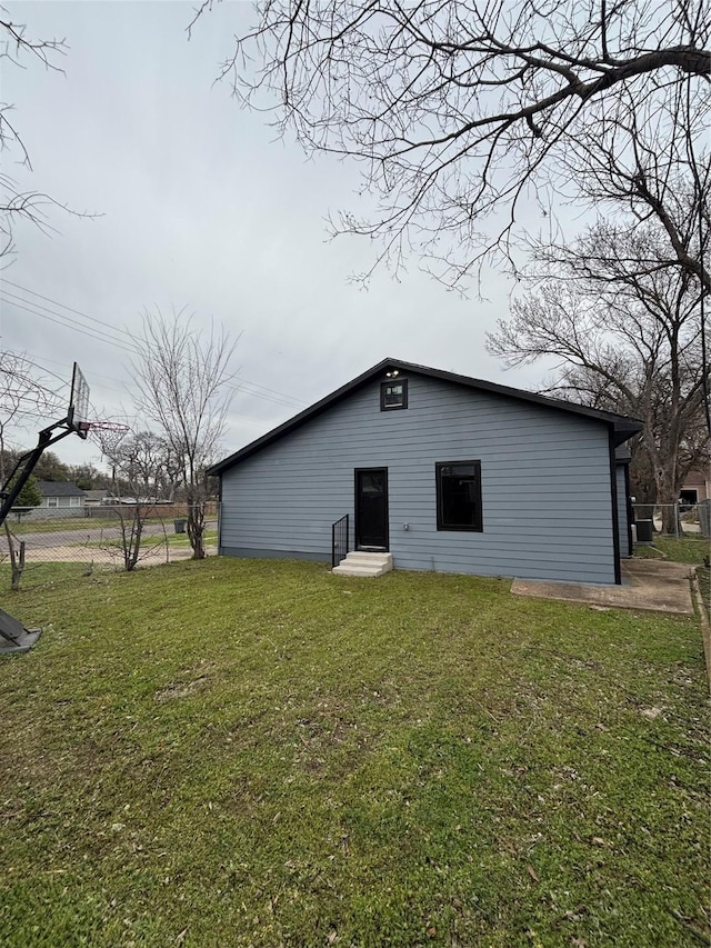 rear view of house with entry steps and a yard