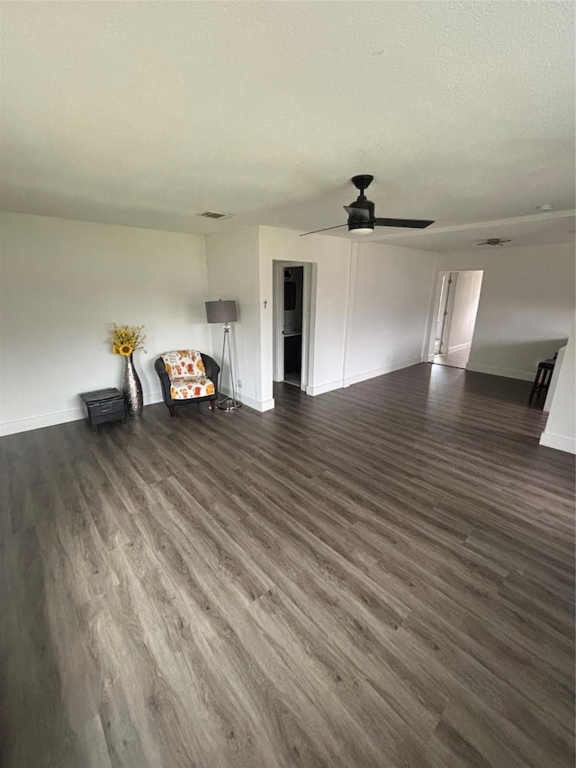 unfurnished living room featuring visible vents, a textured ceiling, baseboards, and dark wood-type flooring