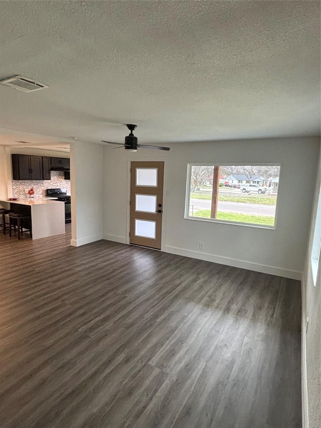 unfurnished living room featuring dark wood-style flooring, visible vents, and baseboards