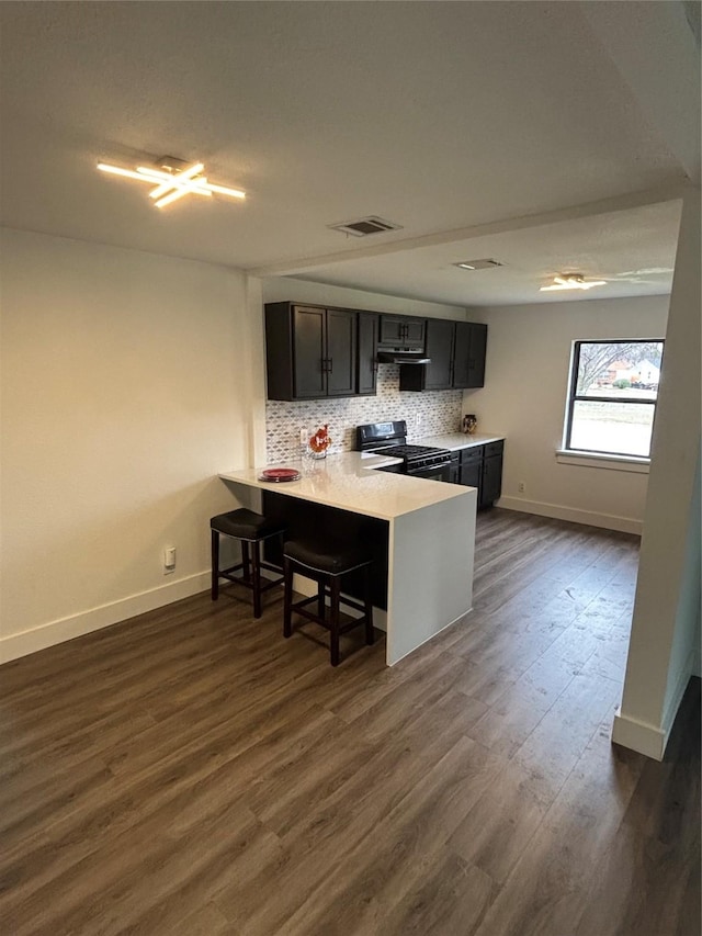 kitchen featuring a peninsula, visible vents, light countertops, backsplash, and gas stove