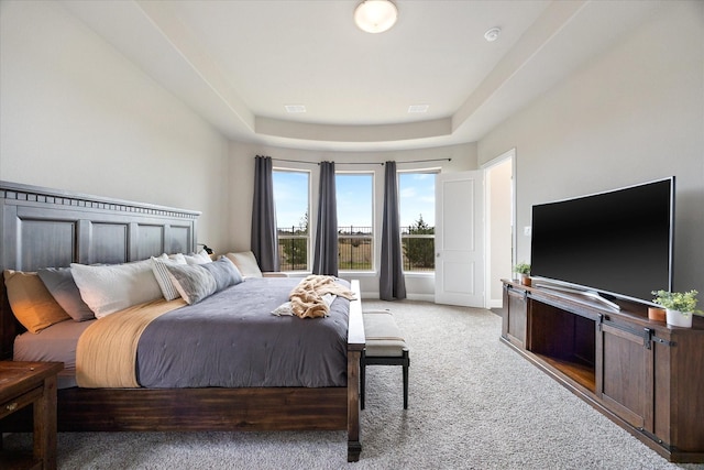 bedroom with visible vents, baseboards, a tray ceiling, and light colored carpet