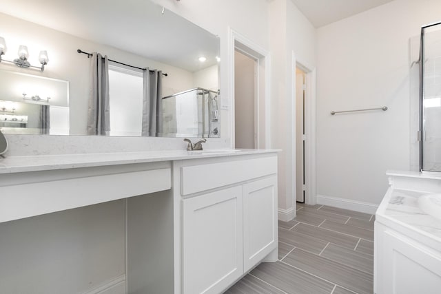 bathroom with a shower stall, baseboards, and vanity