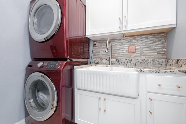 washroom featuring a sink, stacked washing maching and dryer, and cabinet space