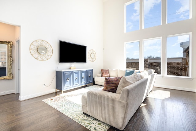 living area with a high ceiling, wood finished floors, and baseboards