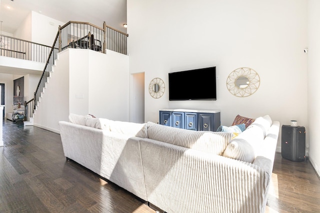 living area with stairs, a high ceiling, wood finished floors, and baseboards