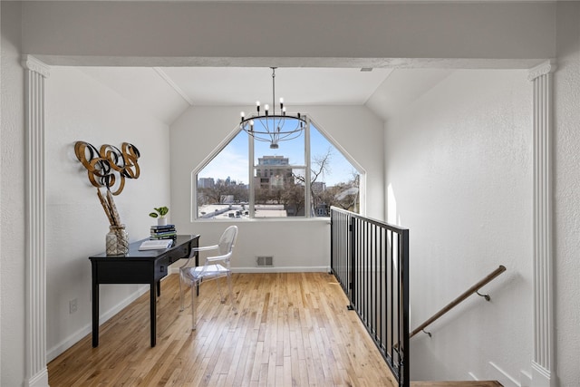 interior space featuring light wood-style flooring, an upstairs landing, visible vents, vaulted ceiling, and an inviting chandelier