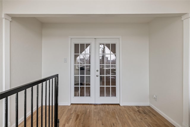 doorway with french doors, baseboards, and light wood finished floors