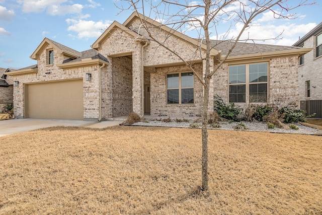 view of front of property with brick siding, roof with shingles, central AC unit, a garage, and driveway