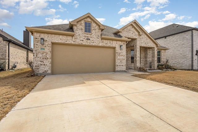 french country style house with concrete driveway, brick siding, an attached garage, and a shingled roof